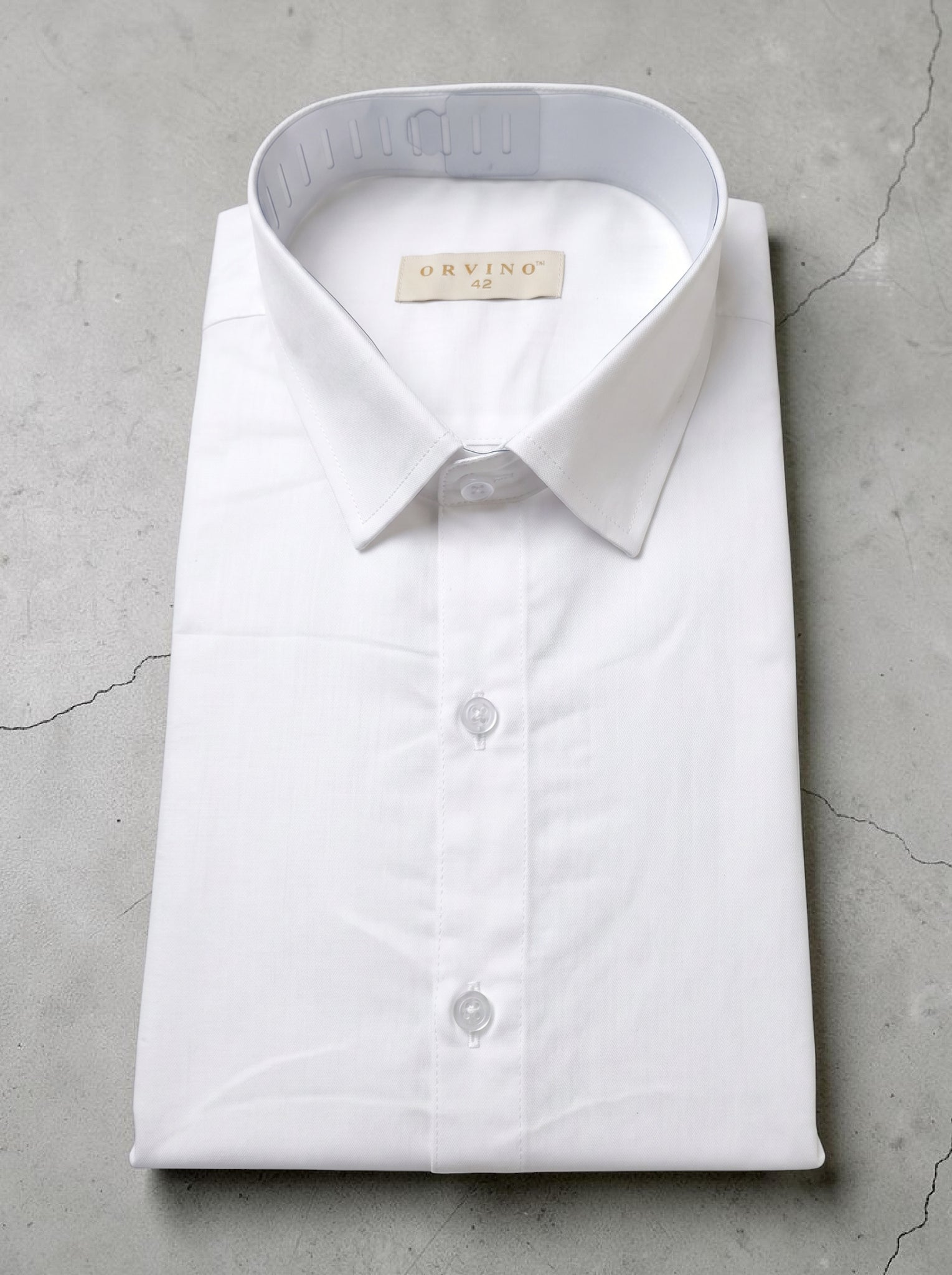 Folded white dress shirt with a brand label on a gray concrete surface